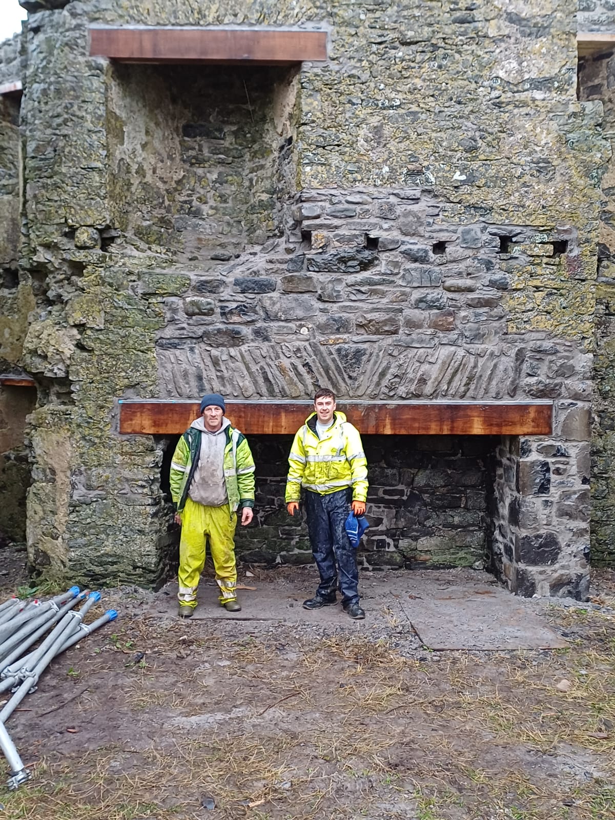 Two volunteers in front of the restored arch, 31 October 2025
